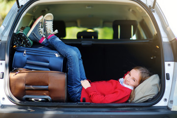 Wall Mural - Adorable little girl ready to go on vacations with her parents. Kid relaxing in a car before a road trip.