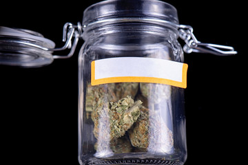 cannabis buds (maui skunk strain) on a glass jar isolated over black background