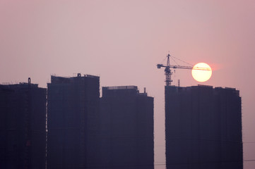 Poster - sunrise in fog day with skyscraper construction silhouette