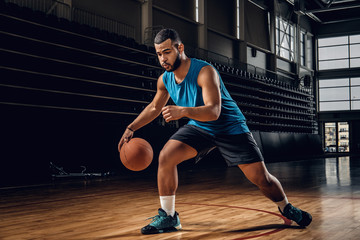 Wall Mural - Professional basketball player in an action in basketball field.