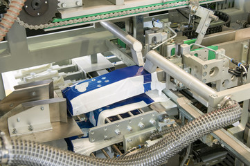 factory and equipment for the production of female sanitary napkins. packing equipment for women's sanitary napkins on a conveyor belt closeup