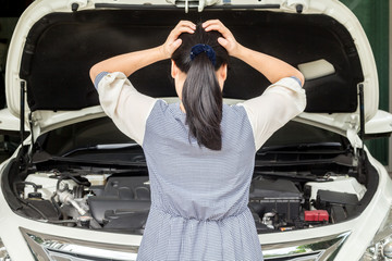 Woman looking under hood of breakdown car