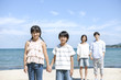 © amanaimages - Family of four standing on the beach