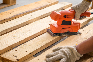 Wood sanding machines , Carpenter working with electrical sander on pine floor or table surface