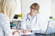 © sepy - Doctor and her patient. Shot of a middle aged smiling female doctor sitting in front of laptop and meeting with her patient.