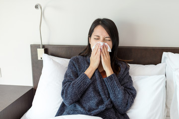 Wall Mural - Woman sneezing on bed