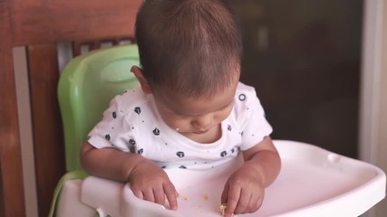 Wall Mural - 1 year old Asian baby eating food by himself