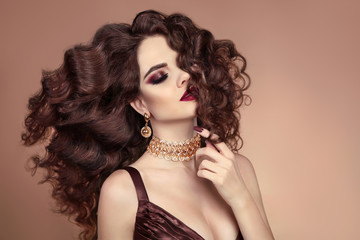 Beautiful hair. Healthy hairstyle. Brunette Girl portrait. Beauty Eye makeup. Fashionable sexy Woman advertising shampoo and fashion precious golden jewelry set.