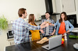 © W PRODUCTION - group of friends, four people man and woman at home cooking, drinking wine and preparing food meal together in the kitchen