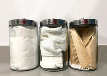 Three Glass Jars On Medical Office Counter With Non-sterile Q-tips, Tongue Depressors, 4x4's And Cotton Ready For Use. Clean, Not Sterile Supplies.