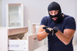 Robber wearing balaclava stealing valuable things