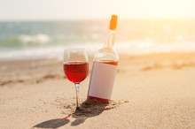 Glass Of Red Rose Wine And Bottle On The Beach At The Summer Sunny Day. Sea On The Background