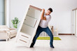 © Elnur - Young man moving furniture at home
