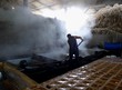 Man working hard in a hot steam filled shed, sugar refinery.