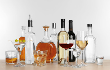 Wall Mural - Table with different bottles of wine and spirits on light background