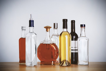 Wall Mural - Table with different bottles of wine and spirits on light background