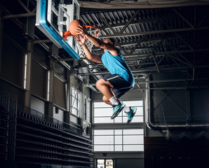 Wall Mural -  Black basketball player in action in a basketball court.