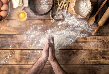 Man preparing bread dough on wooden table in bakery