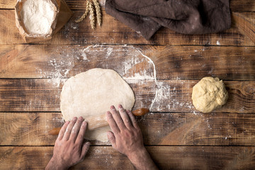 Poster - Male hand rolled dough for pizza on a wooden table