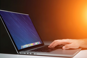 Hand typing on a keyboard of laptop with operating system screen on background