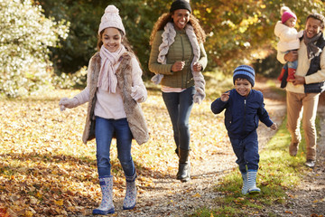 Wall Mural - Family Running Along Path Through Autumn Countryside