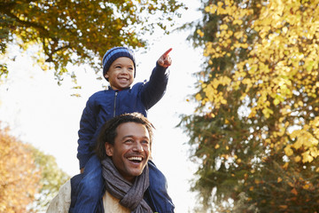 Wall Mural - Autumn Walk With Father Carrying Son On Shoulders