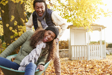 Wall Mural - Man In Autumn Garden Gives Woman Ride In Wheelbarrow