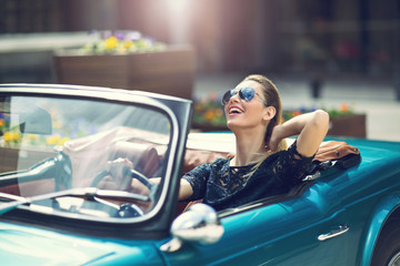 Portrait of beautiful sexy fashion woman model in sunglasses sitting in luxury retro cabriolet car