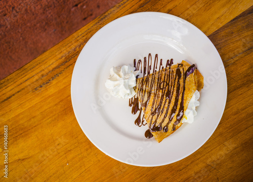 Delicious yummy crepe filled with cream and chocolate syrup topping © Ossobüko