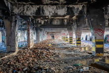 Abandoned Building Covered In Soot And Graffiti With Ruble And Garbage On The Floor In An Industrial Area Like A Post Apocalyptic  Scene