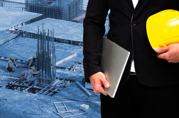 Wall Mural - double exposure of businessman hold in hand yellow safety helmet and laptop computer notebook industrial concept on construction site workers background, color tone effect.