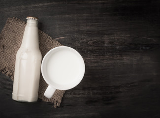 Wall Mural - Milk cup and bottle milk on dark wooden table,Top view with copy space