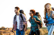© Cookie Studio - Young cheerful travelers with backpacks smiling, walking in canyon.