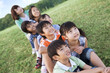 © amanaimages - School children and female teacher sitting in field, looking away