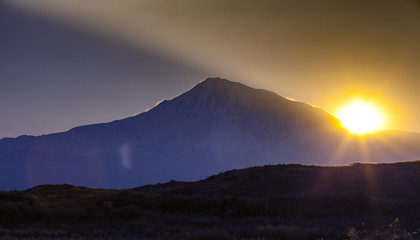 Sunset over color mountain silhouette with rays