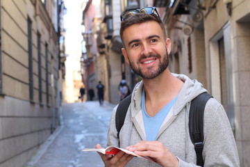 Wall Mural - Handsome tourist consulting a guide during a travel around Europe 