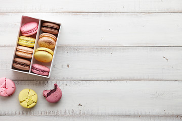 Wall Mural - Box of colorful french macarons on white wooden boards, top view