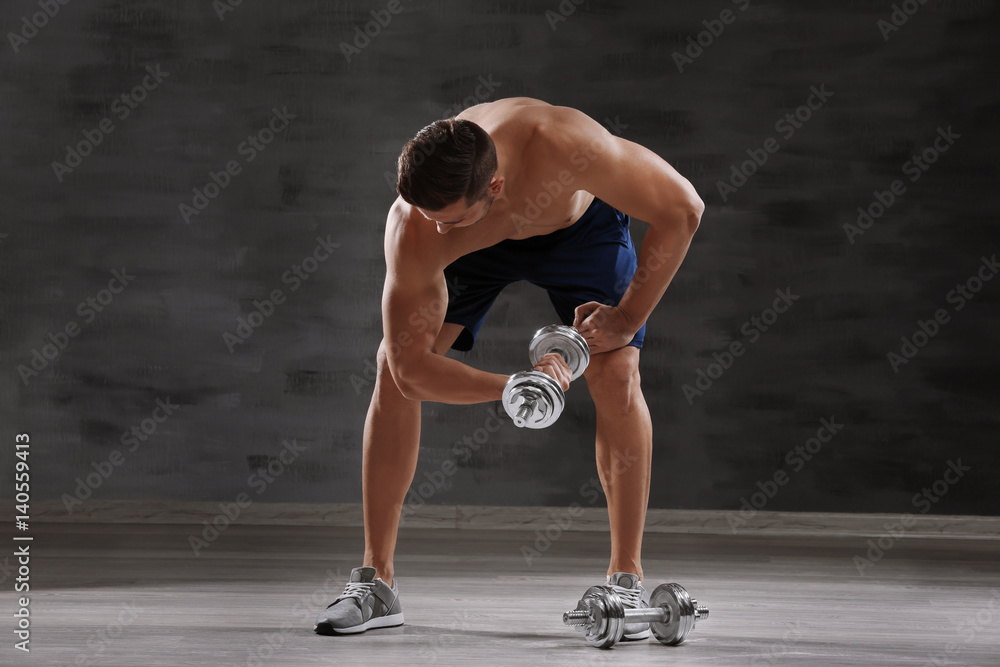 Sporty man doing exercises with dumbbells in gym