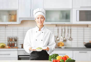 Female chef holding prepared dish in kitchen