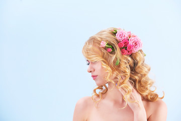 Wall Mural - Beautiful young woman with flowers in hair on light background