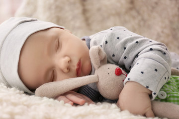 Wall Mural - Cute little baby with bunny toy sleeping on plaid at home, closeup