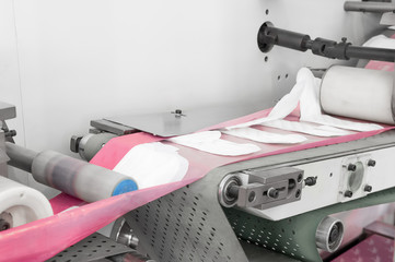 Wall Mural - factory and equipment for the production of female sanitary napkins. women hygiene pads on a conveyor belt closeup