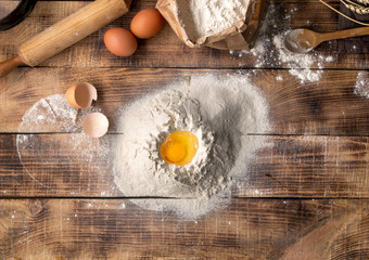 Poster - Egg yolk in flour on a wooden background
