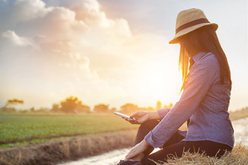 Woman relaxing with smartphone in hand on sunset rural nature background