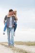 © moodboard - Full length of young man giving piggyback ride to woman on trail at field