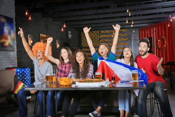 Wall Mural - Cheerful friends watching soccer game in sport bar