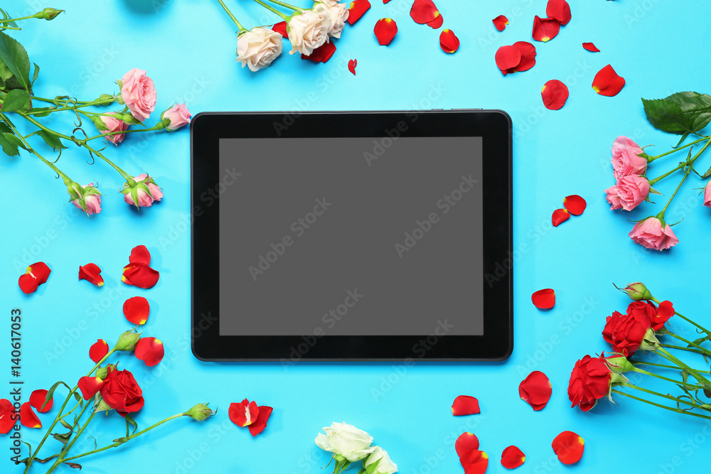 Tablet with flowers on table, top view