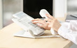 © Africa Studio - Woman dialing number on telephone in office