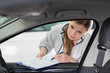 © MDBPIXS - Female maintenance engineer with clipboard examining car's interior in workshop