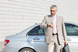 © MDBPIXS - Businessman checking the time in front of car outdoors